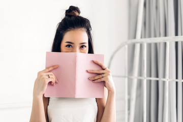Young woman relaxing reading book on bed at home