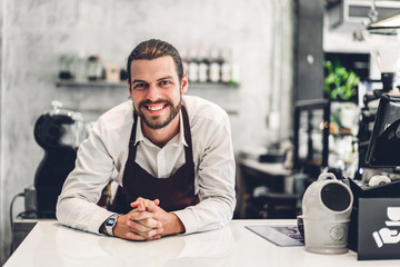 Portrait of handsome bearded barista man small business owner working behind the counter bar in a...