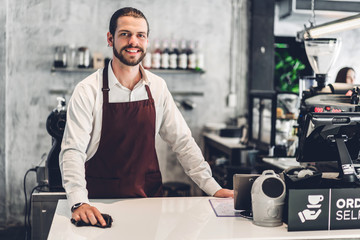 Portrait of handsome bearded barista man small business owner working behind the counter bar in a cafe