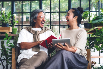 Happy family senior adult elderly asia couple holding and use  digital tablet computer at green house.Retirement concept