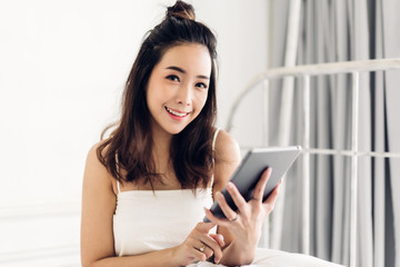 Happy woman relaxing using tablet computer on the bed at home.technology and communication concept