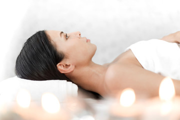 Beautiful young woman beauty skin treatment relaxing lying on towel in massaging and spa salon
