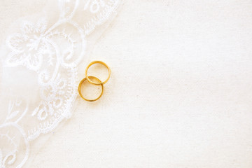 Obraz na płótnie Canvas Beautiful flat lay top view beautiful gold couple wedding rings on elegant lace on white canvas with copy space background