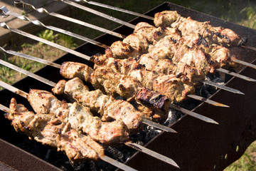 Kebab grilling on metal skewers. Meat on the grill. Close up.