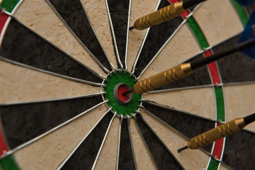 One of three darts hits the center of the darts board also known as "bulls eye" .