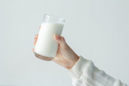 Young woman with white sweater holding drinking milk glass in her hand. Health care concept.