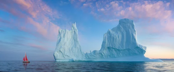 Kleines rotes Segelboot, das während der Mitternachtssonnensaison des Polarsommers zwischen schwimmenden Eisbergen im Disko Bay-Gletscher kreuzt. Ilulissat, Grönland. Kulturerbe der UNESCO © Michal