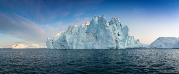 Iceberg at sunset. Nature and landscapes of Greenland. Disko bay. West Greenland. Summer Midnight Sun and icebergs. Big blue ice in icefjord. Affected by climate change and global warming. - Powered by Adobe