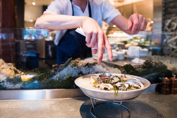 restaurant worker introducing oyster dish to customer