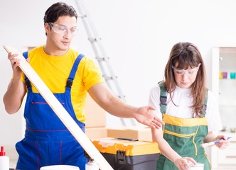 Man explaining woman woodworking tips in wood workshop