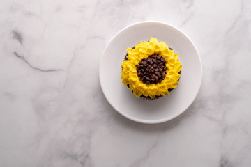 Beautiful sunflower decorated chocolate cupcake on marble table.