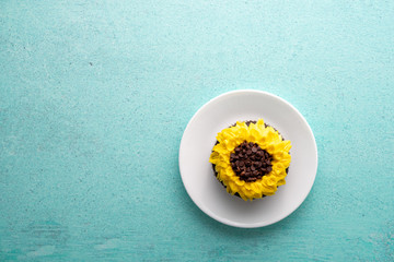 Beautiful sunflower decorated chocolate cupcake on aqua pastel background