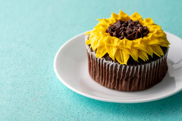 Beautiful sunflower decorated chocolate cupcake on aqua pastel background