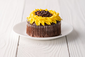 Beautiful sunflower decorated chocolate cupcake on white wood background