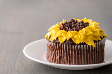 Beautiful sunflower decorated chocolate cupcake on dark wood background