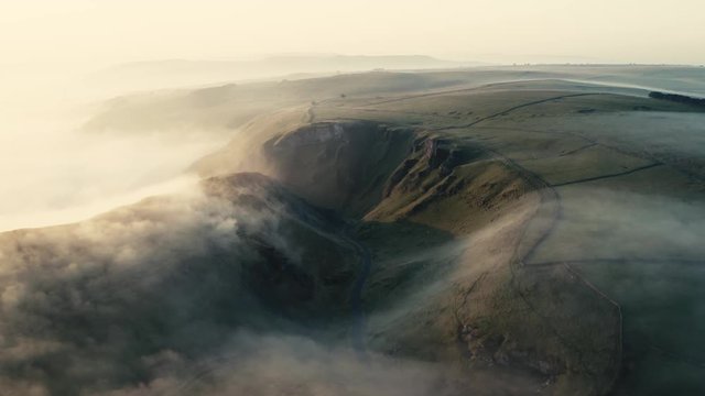 a drone revealing the rolling mist/ cloud inversion over Winnats pass, caslteton peak district. sunrise over hope valley