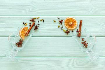 Mulled wine concept. Spices and dried orange in glasses on green wooden background top view copy...