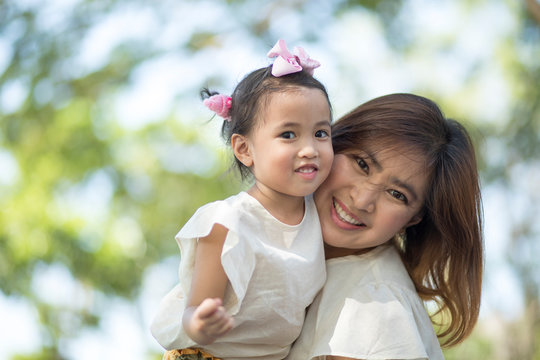close up happiness face of asian mother and little daughter toothy smiling outdoor