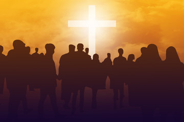 Silhouette crowd standing in front of white cross with sunset sky background. Christian faith and...