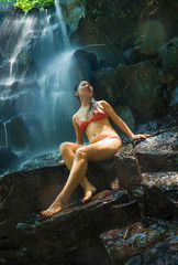 natural portrait of young beautiful and happy Asian Korean woman in bikini enjoying nature at tropical paradise waterfall with magical feeling in soul inspiration