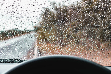 It was raining outside, Looking through the steering wheel to the window of the car, it saw rain on the glass