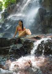 natural portrait of young beautiful and happy Asian Chinese woman in bikini enjoying nature at tropical paradise waterfall with magical feeling in soul inspiration