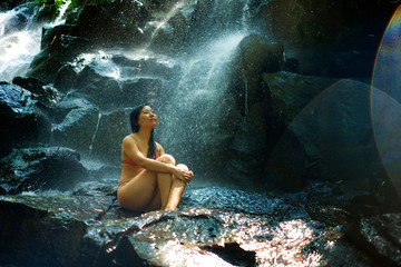 natural portrait of young beautiful and happy Asian Chinese woman in bikini enjoying nature at tropical paradise waterfall with magical feeling in soul inspiration