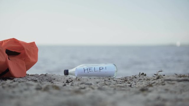 Message Help in bottle lying on shore, concept of searching survivors of crashes