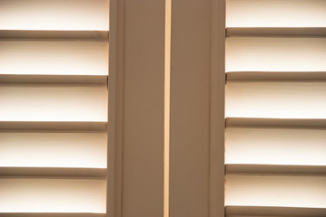 Soft light through wooden blind shutters closeup.