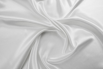Fototapeta premium Delicate satin draped fabric white texture for festive backgrounds