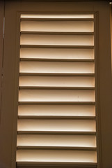 Soft light through wooden blind shutters in closed position.