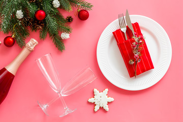 Christmas table setting with fir tree and bottle with glasses on pink background top view