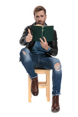 man sitting with a book and ok sign