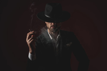 enigmatic young man smoking on black background
