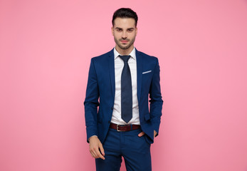 attractive young man wearing navy blue suit on pink background