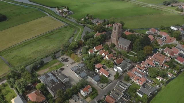 Aerial rotating pan around the centre of the village Ransdorp with its agrarian surroundings near the city of Amsterdam in The Netherlands with clouds