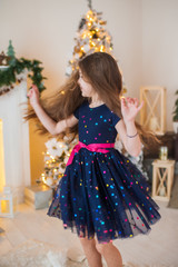 Portrait of a beautiful girl who dances in a room with a Christmas tree and garlands