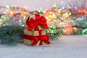 Christmas card. Two gifts with a red bow on a wooden background, fir branch. Bokeh