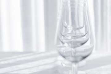 Several empty wine glasses in white grey shades on the white tablecloth