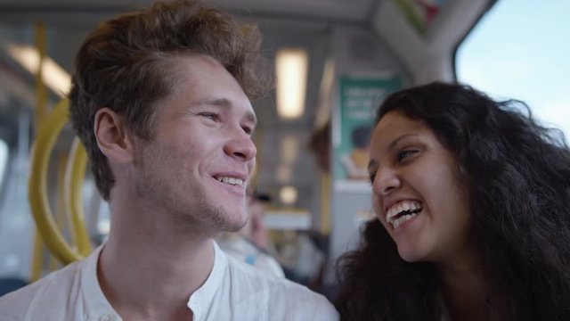 A young man and woman smiling and laughing on the subway.