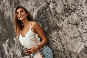 Beautiful girl posing over concrete background during outdoor photoshoot