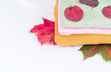 cosy autumn - knitted sweaters, chestnuts and autumn leaves on white background