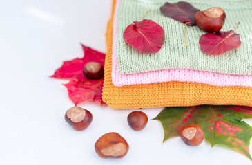 Obraz na płótnie Canvas cosy autumn - knitted sweaters, chestnuts and autumn leaves on white background