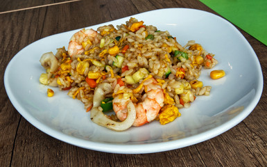 Rice with mixed seafood and eggs in bowl plate on a wooden table. Asian traditional food: Yaki Meishi Kaisen