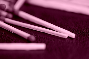 Scattered matches on dark background close up. Pink color toned