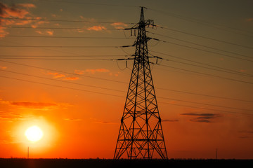 Silhouette High voltage electric towers at sunset time. High-voltage power lines. Electricity distribution station