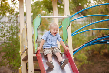 A boy with Down syndrome plays in the playground. Genetic disease in a child.