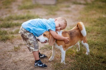 A boy with Down syndrome plays in the playground. Genetic disease in a child. Toddler hugs a dog.
