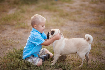 A boy with Down syndrome plays in the playground. Genetic disease in a child. Toddler hugs a dog.