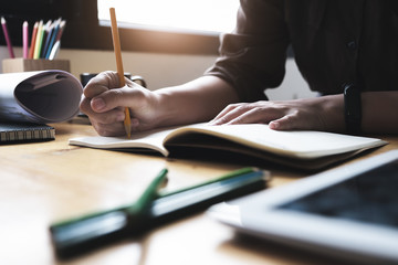 Young woman working with color pencil and notebook and tablet for using design or creative  to...